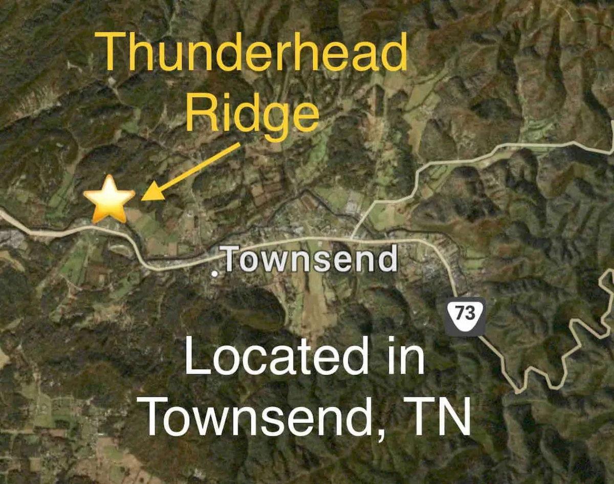 A sweeping view of Thunderhead Ridge and the surrounding Townsend area, featuring rolling hills, lush trees, and a glimpse of local roads. The landscape creates a sense of adventure and natural splendor.