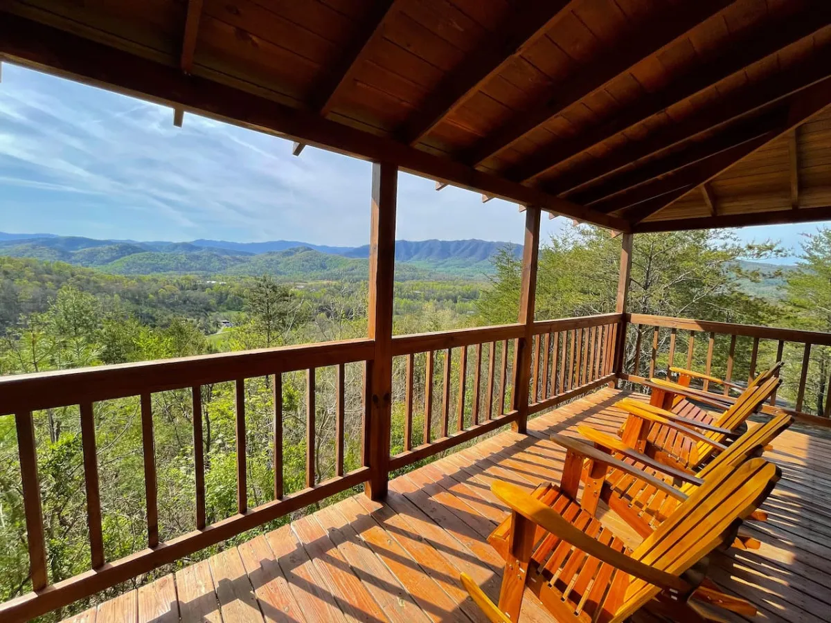 A peaceful exterior deck featuring sturdy wooden chairs overlooking the mountains, framed by a classic wooden railing. The scene suggests moments spent relaxing or sharing stories with loved ones, all while enjoying expansive views and the ambiance of nature.