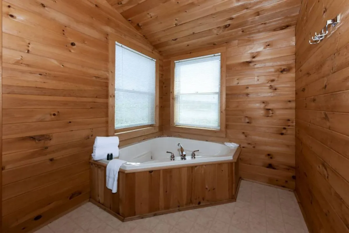 A spa-like bathroom scene with a jacuzzi tub surrounded by warm wooden walls and windows that let in natural light. The space feels calm and inviting, ideal for soaking and unwinding.